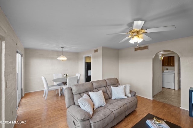 living room with ceiling fan, washer / dryer, and light hardwood / wood-style flooring