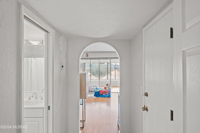 hallway featuring hardwood / wood-style floors, sink, and a textured ceiling