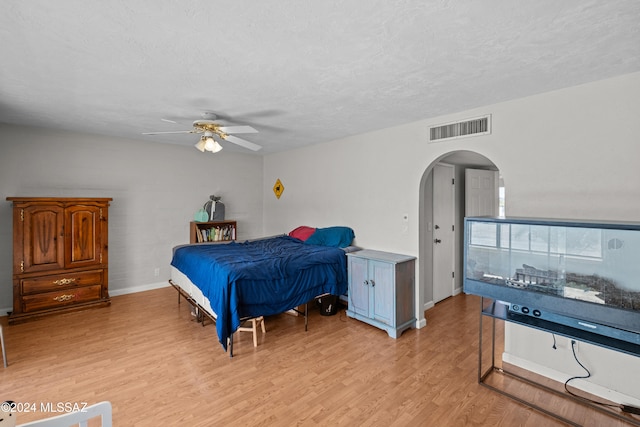 bedroom featuring ceiling fan, light hardwood / wood-style flooring, and a textured ceiling