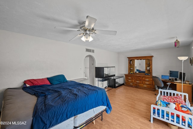 bedroom with a textured ceiling, light wood-type flooring, and ceiling fan