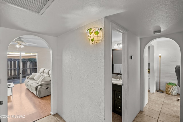 hall with sink, light tile patterned floors, and a textured ceiling