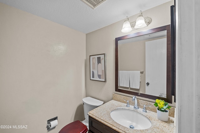 bathroom featuring a textured ceiling, vanity, and toilet