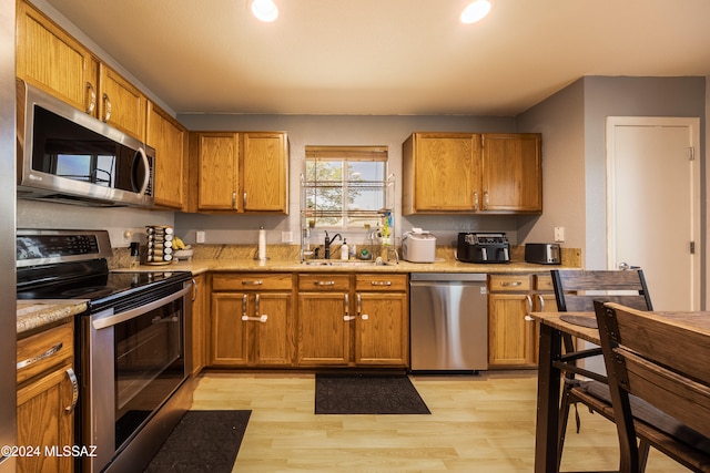 kitchen with sink, stainless steel appliances, and light wood-type flooring