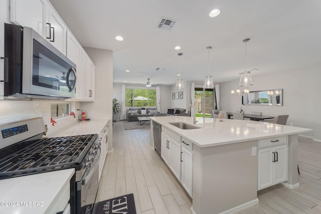 kitchen featuring white cabinetry, appliances with stainless steel finishes, sink, and a center island with sink