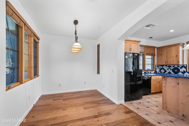 kitchen with light hardwood / wood-style floors, black appliances, sink, backsplash, and pendant lighting