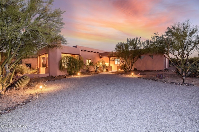 pueblo-style house with gravel driveway and stucco siding