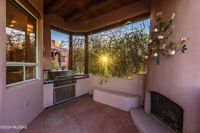 patio terrace at dusk featuring an outdoor kitchen, heating unit, and grilling area