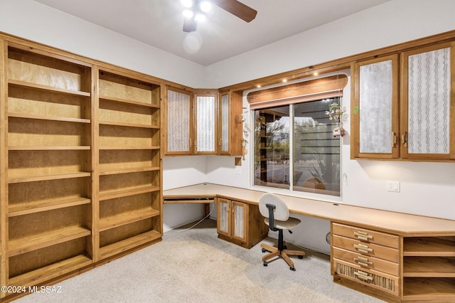 carpeted office featuring built in desk and ceiling fan