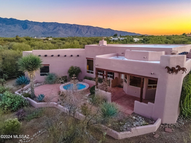 back of property featuring stucco siding, a patio, and a mountain view