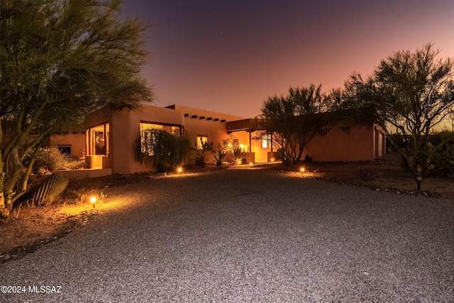 pueblo revival-style home featuring gravel driveway