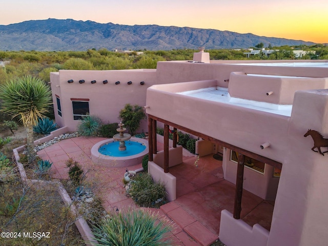 pool at dusk with a patio area and a mountain view