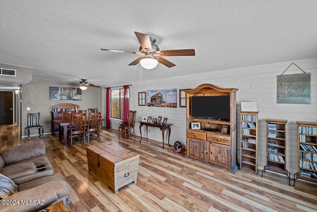 living room featuring a textured ceiling, light wood-type flooring, and ceiling fan