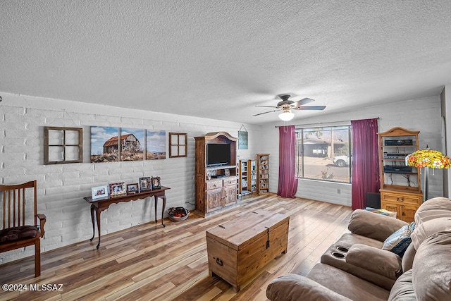 living room featuring ceiling fan, wood-type flooring, and a textured ceiling