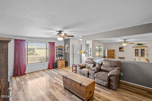 living room featuring ceiling fan, a healthy amount of sunlight, a textured ceiling, and light hardwood / wood-style flooring