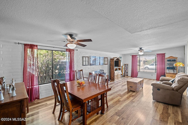 dining space with brick wall, a textured ceiling, and hardwood / wood-style flooring