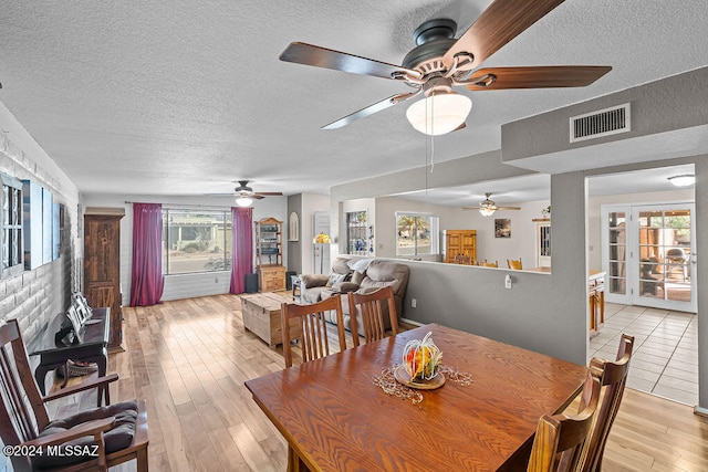 dining room with a textured ceiling, light hardwood / wood-style floors, and ceiling fan