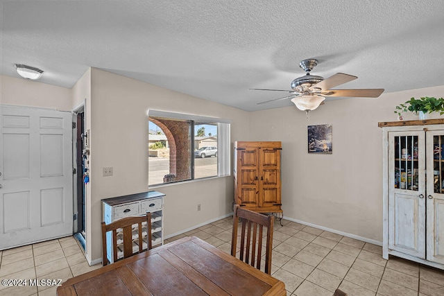 dining space with ceiling fan, a textured ceiling, lofted ceiling, and light tile patterned flooring