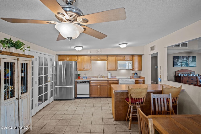 kitchen featuring light tile patterned floors, a textured ceiling, sink, french doors, and stainless steel appliances