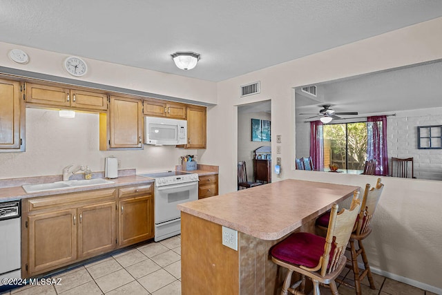 kitchen with kitchen peninsula, ceiling fan, light tile patterned floors, sink, and white appliances