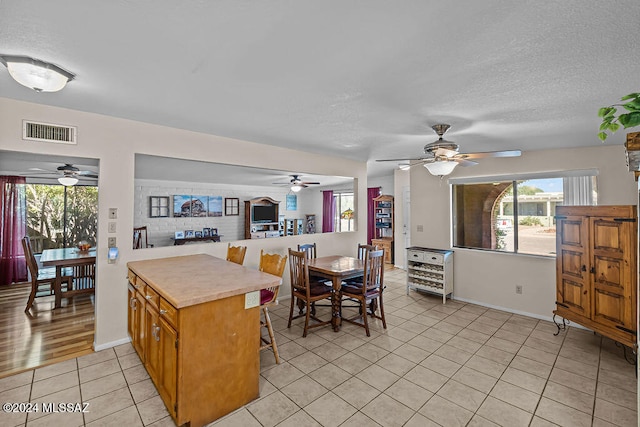 kitchen with light tile patterned floors, a textured ceiling, a breakfast bar, and kitchen peninsula