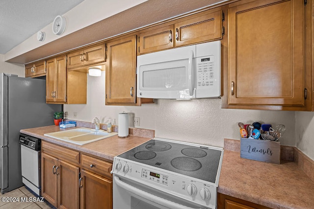 kitchen with white appliances, light tile patterned flooring, and sink