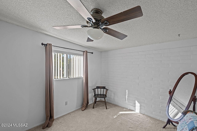 interior space featuring ceiling fan, brick wall, a textured ceiling, and light colored carpet