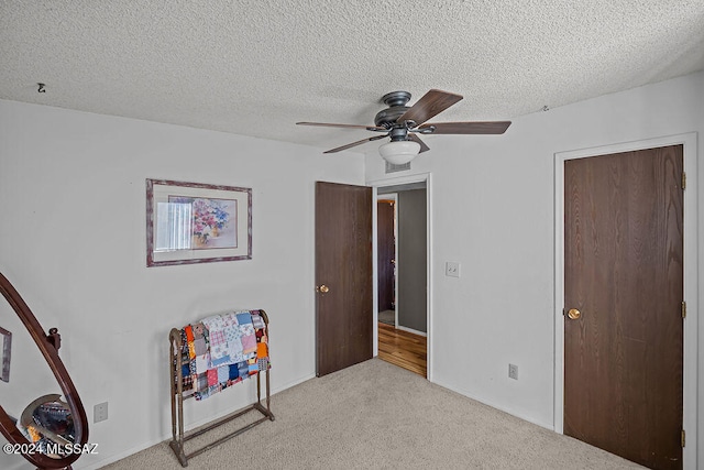 interior space with light carpet, a textured ceiling, and ceiling fan