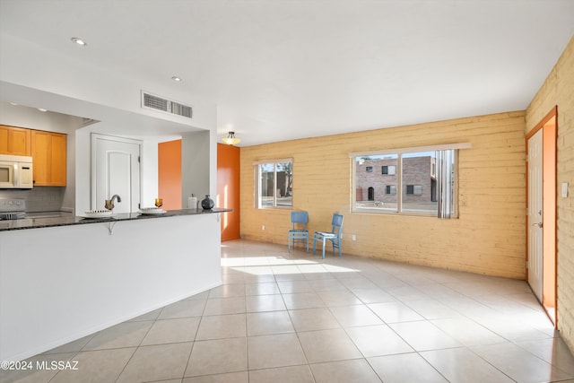 kitchen featuring white appliances, backsplash, light tile patterned floors, and wooden walls