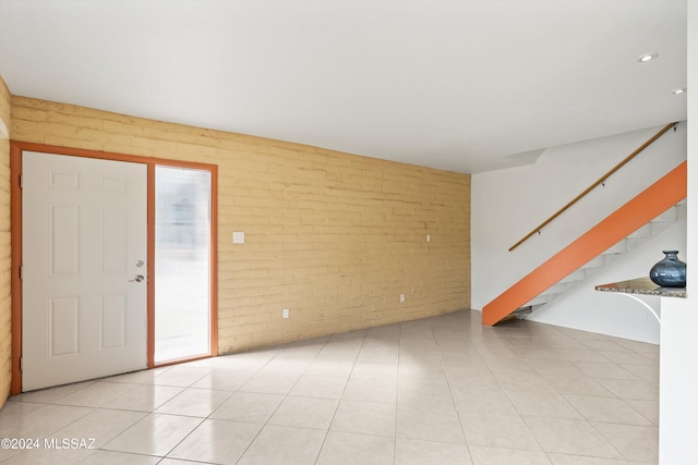 entrance foyer featuring brick wall and light tile patterned floors