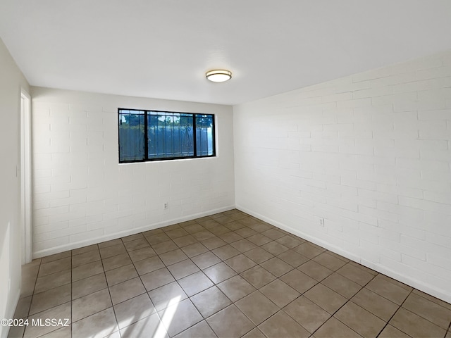 tiled empty room featuring brick wall