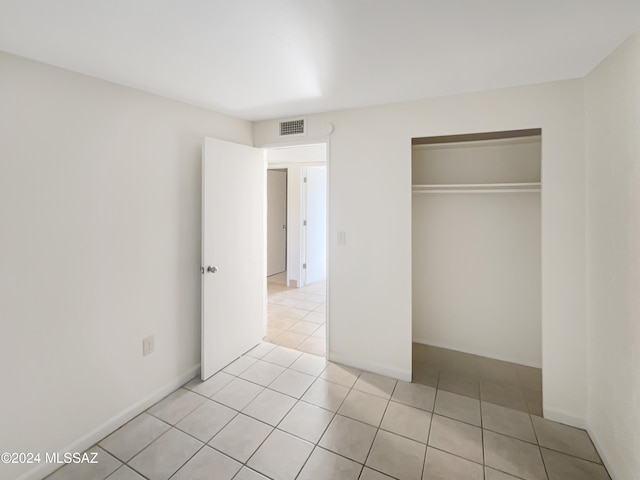 unfurnished bedroom with light tile patterned flooring and a closet