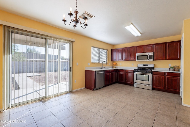 kitchen featuring appliances with stainless steel finishes, sink, light tile patterned flooring, decorative light fixtures, and a notable chandelier