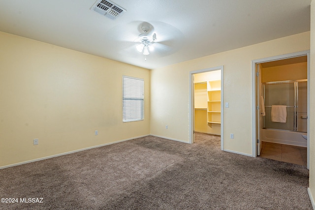 unfurnished bedroom featuring ceiling fan, connected bathroom, a closet, a walk in closet, and light colored carpet