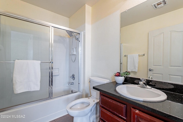 full bathroom with vanity, bath / shower combo with glass door, and toilet