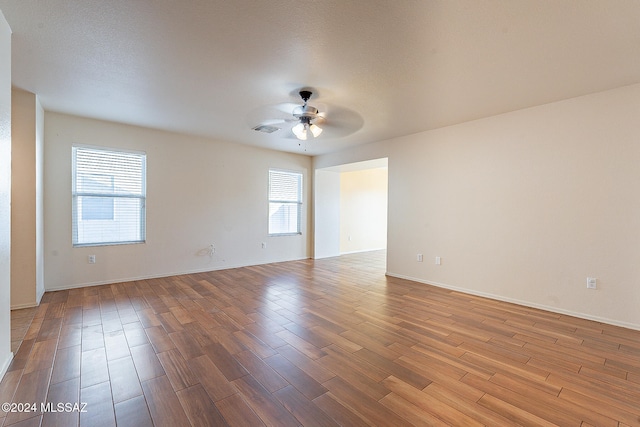 spare room featuring ceiling fan, a textured ceiling, wood-type flooring, and a wealth of natural light