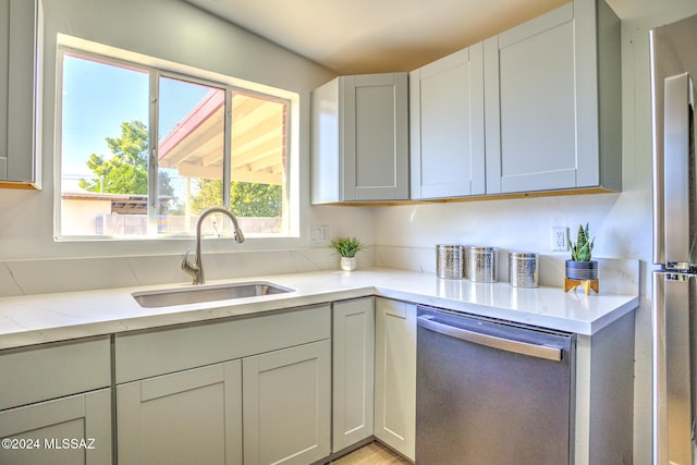 kitchen featuring sink, light stone counters, and appliances with stainless steel finishes