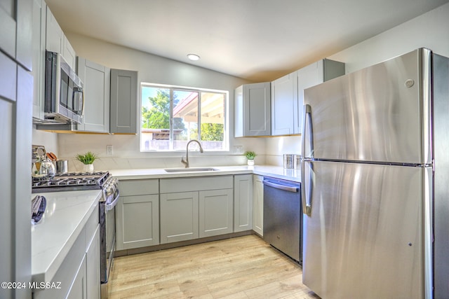 kitchen with stainless steel appliances, light hardwood / wood-style floors, sink, and gray cabinets