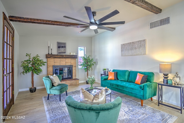 living room featuring a fireplace, vaulted ceiling with beams, ceiling fan, and light hardwood / wood-style flooring