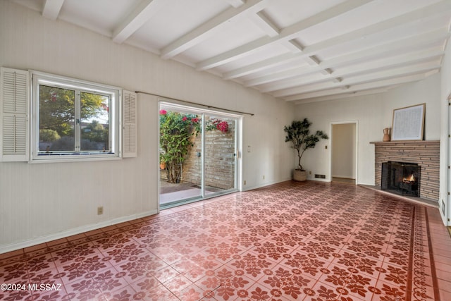 unfurnished living room featuring beamed ceiling, tile patterned flooring, and a stone fireplace