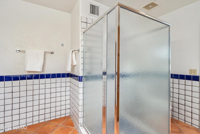 bathroom featuring tile patterned flooring, tile walls, and walk in shower