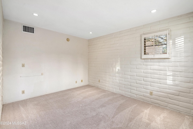 carpeted empty room with brick wall