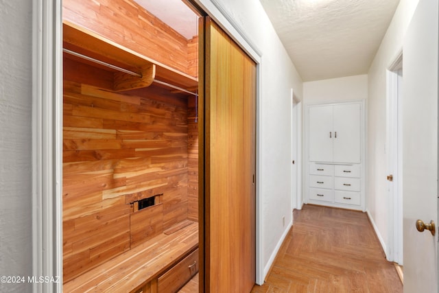 corridor featuring wooden walls and light parquet flooring