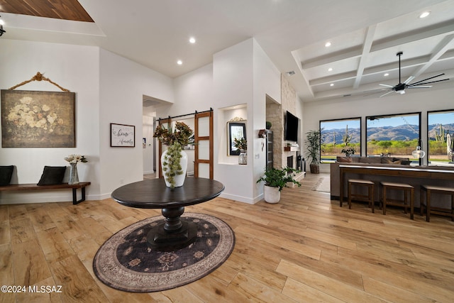 dining area with ceiling fan, a barn door, coffered ceiling, and light wood-style floors