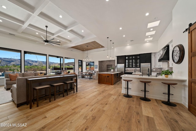 kitchen featuring a breakfast bar area, a mountain view, open floor plan, light countertops, and custom range hood