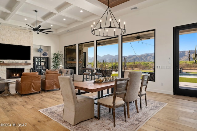 dining room featuring coffered ceiling, a fireplace, a mountain view, and light wood finished floors