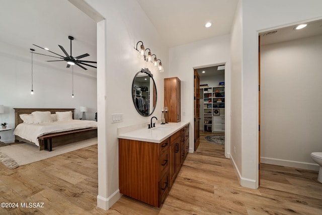 full bathroom with wood finished floors, a walk in closet, vanity, and a ceiling fan