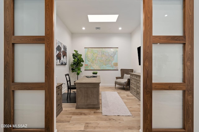 office area with light wood finished floors, a skylight, visible vents, and recessed lighting