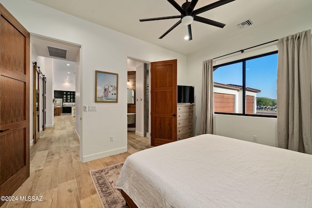 bedroom featuring a barn door, ceiling fan, and light wood-type flooring