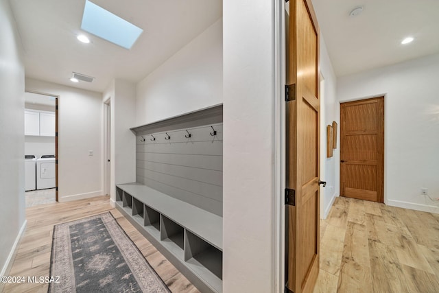 mudroom with a skylight, light hardwood / wood-style floors, and washer and clothes dryer