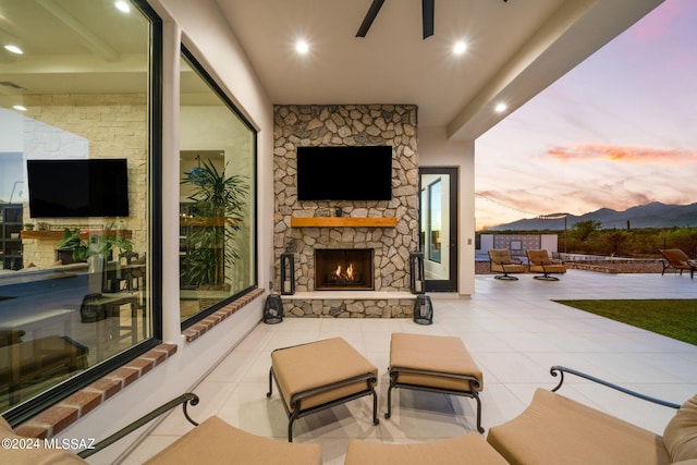 view of patio / terrace with ceiling fan and an outdoor stone fireplace